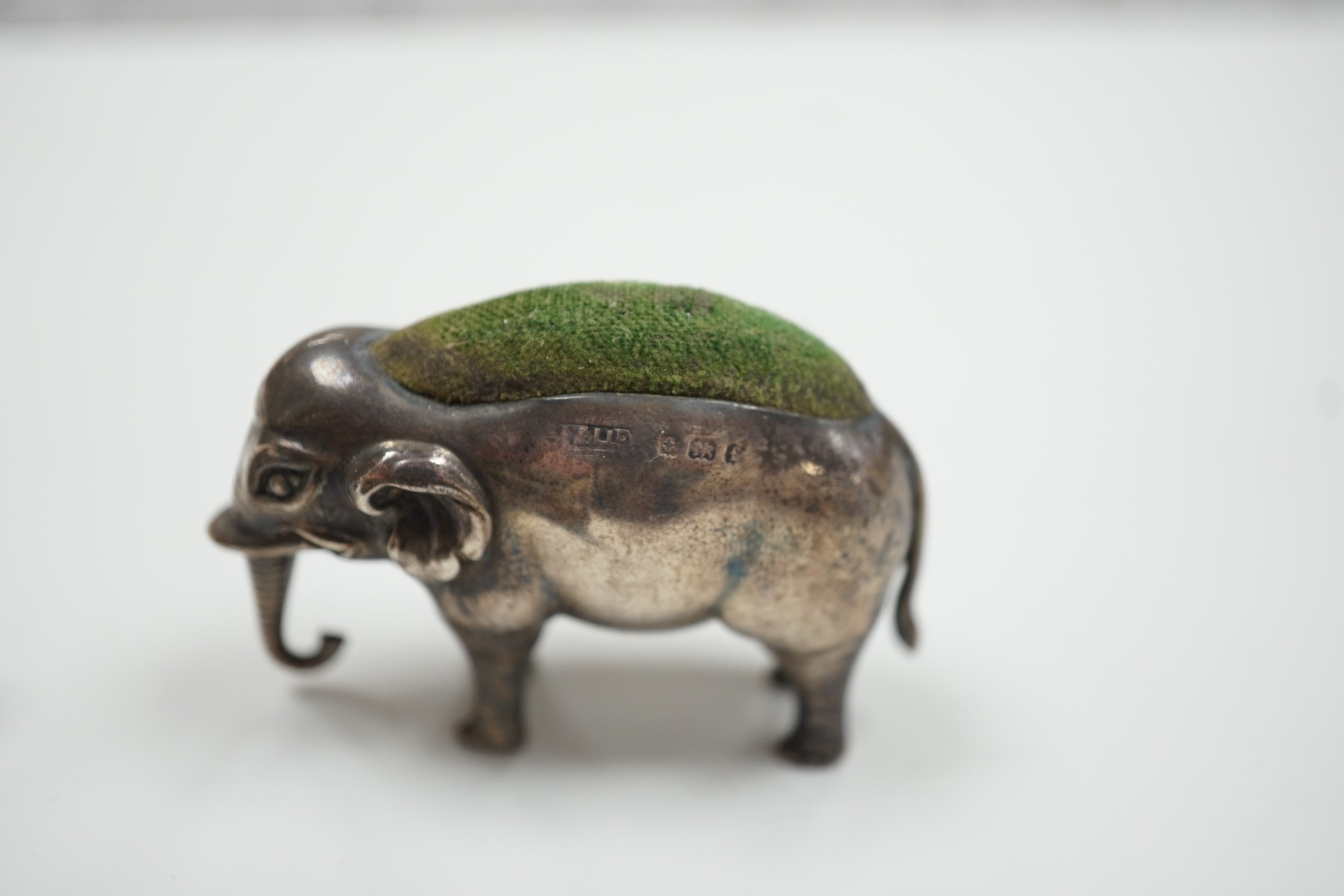 An Edwardian silver elephant pin cushion, Adie & Lovekin, Birmingham, 1905, length 62mm, a similar pig and late Victorian swan pin cushions.